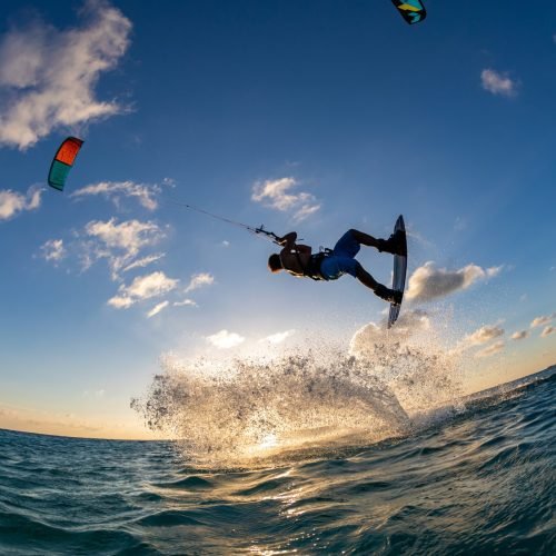A person surfing and flying a parachute at the same time in Kitesurfing. Bonaire, Caribbean